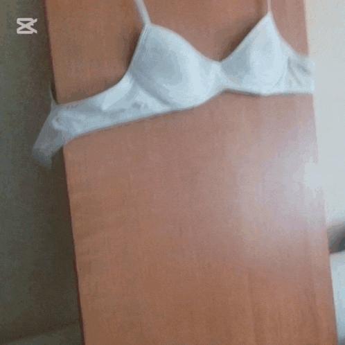 a white bra is wrapped in plastic on a wooden shelf