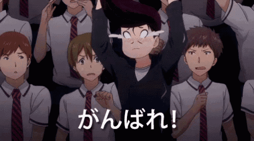 a boy in a black shirt and tie stands in front of a crowd of people with the words " がんばれ " written on the bottom
