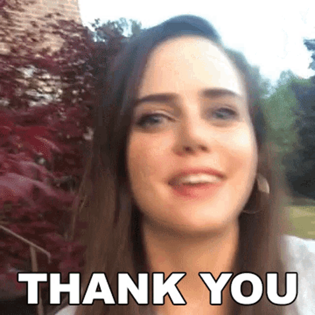 a woman is smiling and saying thank you in front of a bush