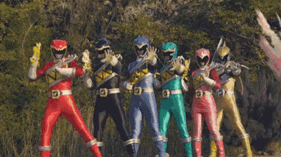 a group of power rangers standing next to each other in a line .