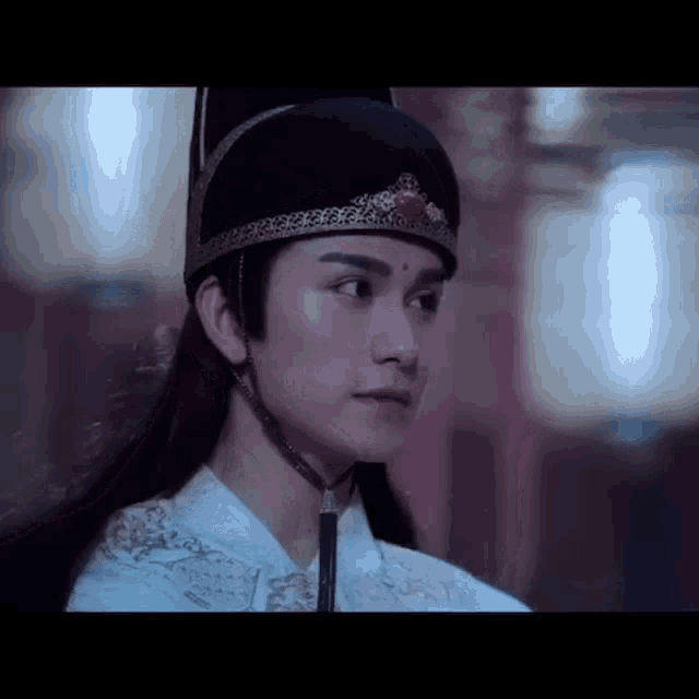 a man with long hair is wearing a black hat and a crown .