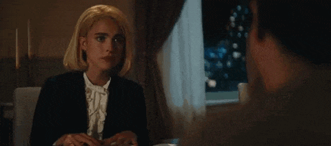 a woman in a wig is sitting at a table with a man and talking to him .