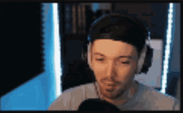 a man wearing headphones is talking into a microphone in front of a screen .