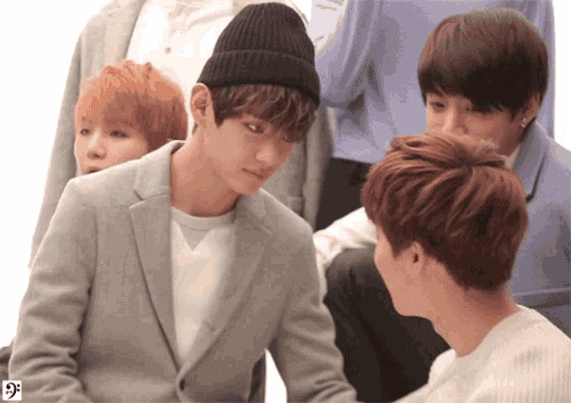 a man wearing a beanie looks at another man