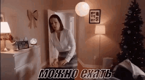 a woman is standing in a room with a christmas tree and a dresser .
