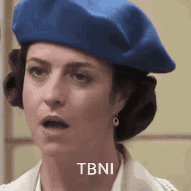 a woman wearing a blue beret says tbni on the bottom