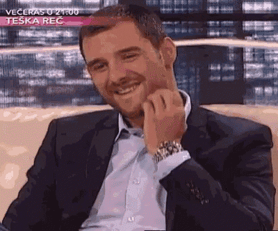 a man in a suit is sitting on a couch smiling .