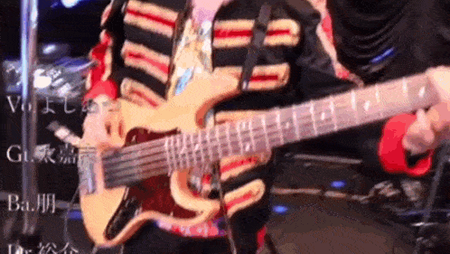a man is playing a guitar on stage with chinese writing in the background .