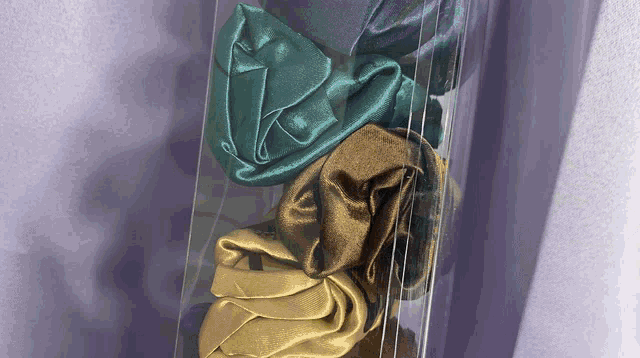 three satin hair scrunchies in a clear plastic box
