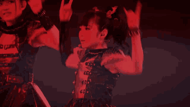 a group of girls are dancing in a dark room with red lights behind them .