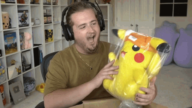 a man wearing headphones is holding a yellow stuffed pikachu