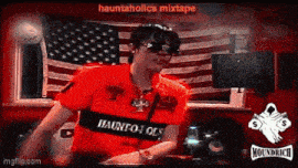 a man wearing sunglasses and a red shirt that says hauntholics mixtape is dancing in front of an american flag .