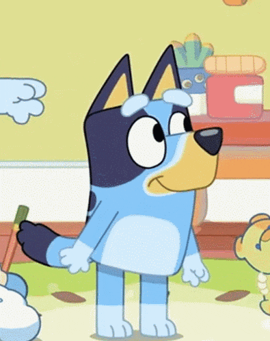 a blue and yellow cartoon dog is standing on a rug holding a brush .