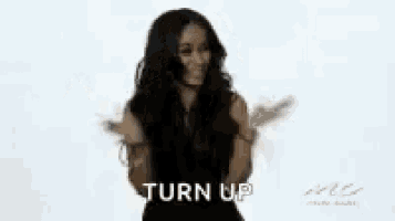 a woman with long hair is dancing in front of a white background and the words turn up are visible .