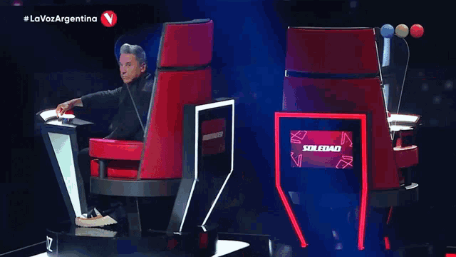 a man sitting in a chair with a screen that says soledad