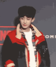 a young man wearing a red and black jacket
