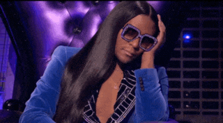 a woman wearing sunglasses and a blue suit is sitting on a couch