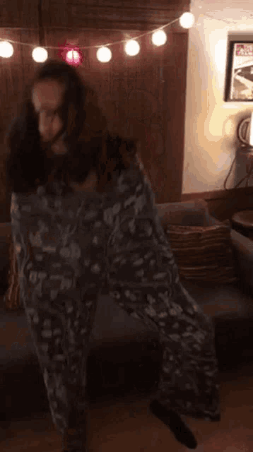 a woman in pajamas is wrapped in a blanket and dancing on a couch .