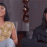 two women are sitting next to each other and smiling .