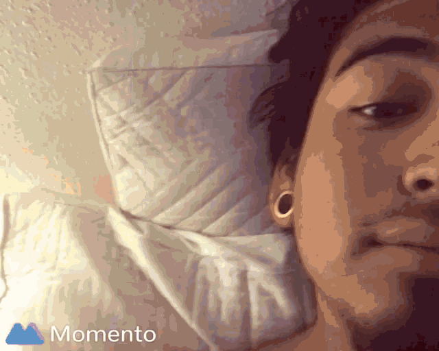 a man is laying on a bed with a momento icon in the corner