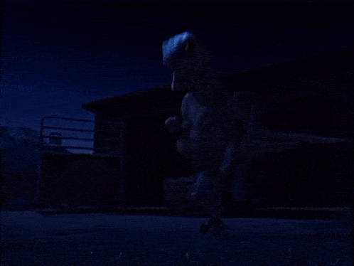 a dinosaur is standing in front of a building in the dark