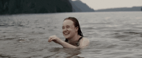 a young woman is swimming in a lake and smiling .