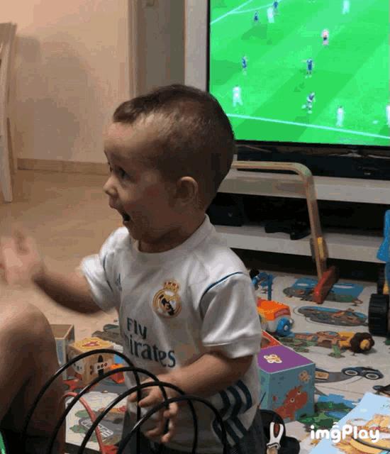 a young boy wearing a fly emirates shirt is playing with toys