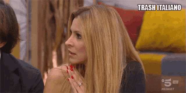 a woman with red nails is sitting in front of a screen that says trash italiano on it
