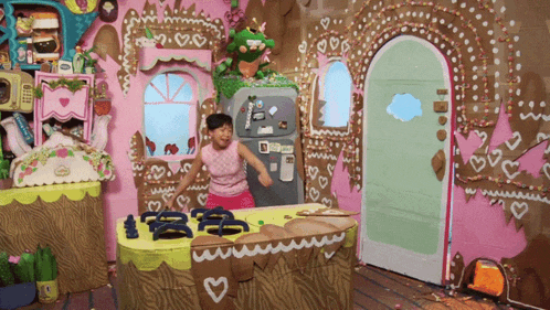 a girl is dancing in front of a gingerbread house with a refrigerator that says ' i love you ' on it