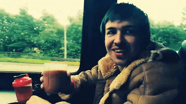 a man in a brown jacket holds a cup of coffee