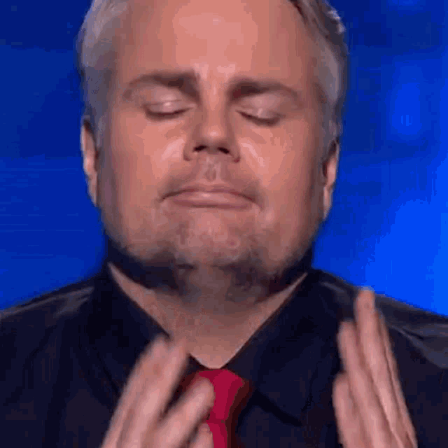 a man with a beard and a red tie is making a funny face .