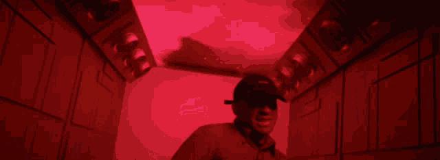 a man in a red shirt and black hat is standing in a hallway