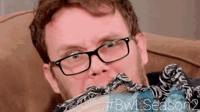 a man wearing glasses is holding a blanket over his face