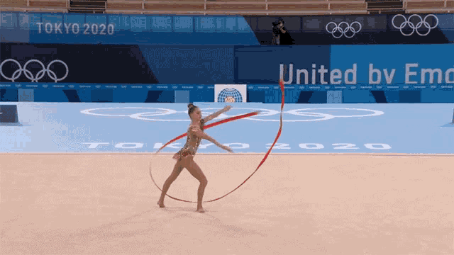 a gymnast performs in front of a sign that says united by emc