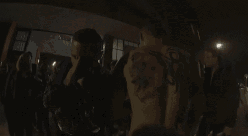 a man with a tattoo on his back is standing in front of a crowd .