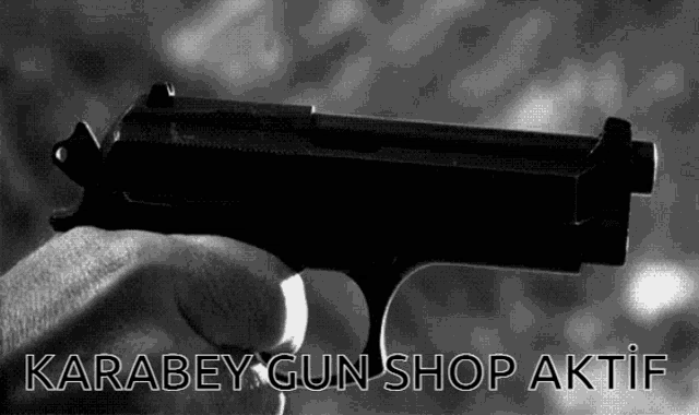 a black and white photo of a person holding a gun with the words karabey gun shop aktif