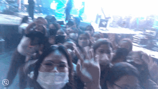 a woman wearing a face mask stands in a crowd of people