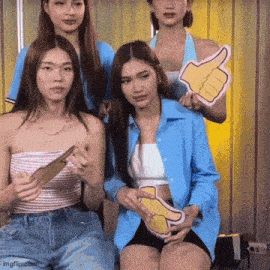 a group of young women are posing for a picture and one is holding a thumbs up sign