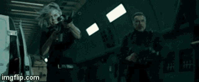 a woman is holding a gun and a man is standing next to her .
