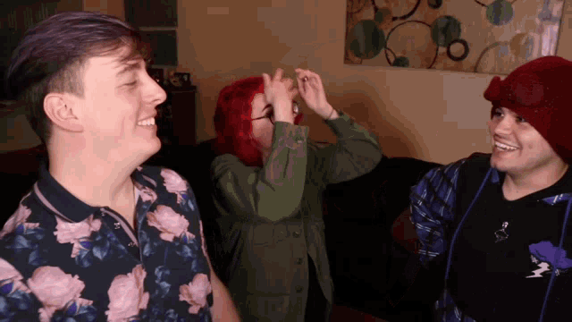 a group of people are standing in a living room and one of them is wearing a floral shirt