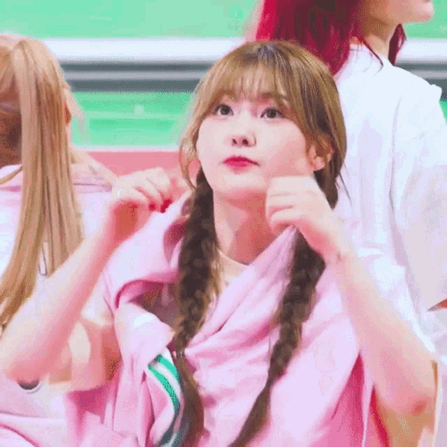 a girl with pigtails is wearing a pink sweater and making a face .