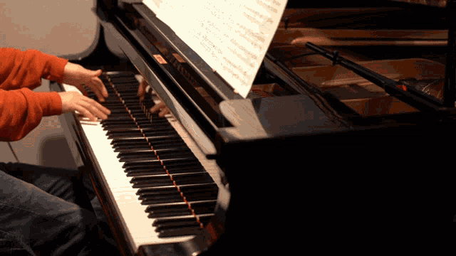a person is playing a piano with a sheet of music on top of it