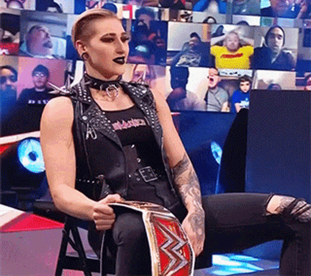 a woman is sitting in a chair holding a championship belt .