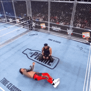 two wrestlers are kneeling on the floor of a wrestling ring sponsored by prime