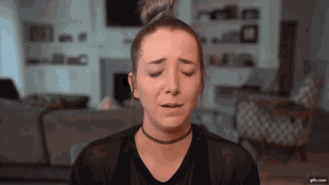 a woman wearing a choker is crying with her eyes closed in a living room .