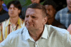 a man is sitting in a crowd of people watching a game and making a funny face .
