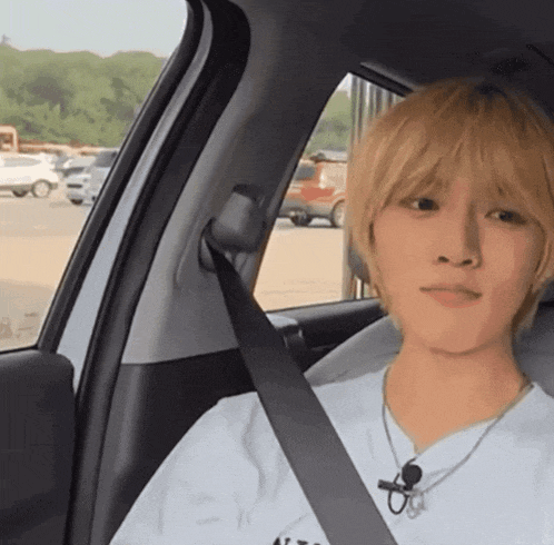 a man with blonde hair is sitting in a car with a black seat belt