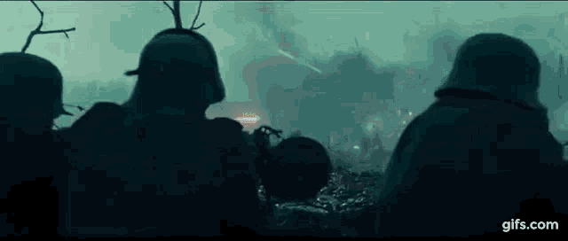 a group of soldiers are standing in a field with smoke coming out of the ground .
