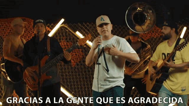 a man singing into a microphone with gracias a la gente que es agradecida below him