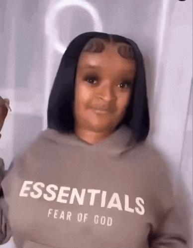 a woman wearing a hoodie that says essentials fear of god on it .